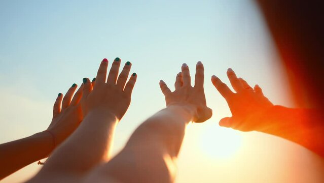 Close up many female hands raised up against blue sky. Friendly team. Gestures, symbols and signs. Participation in public vote. Swing arms to beat of music in dance. Sunny summer outdoor nature.