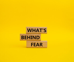 What's behind fear symbol. Concept words What's behind fear on wooden blocks. Beautiful yellow background. Business and What's behind fear concept. Copy space.