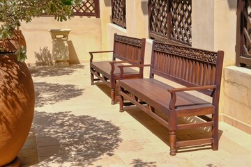 Orient wooden bench handmade with carved ornamental arabesque floral pattern in inner courtyard of middle eastern villa