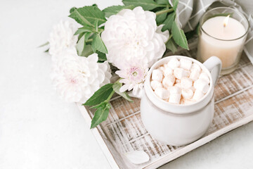 Cocoa or coffee cup with marshmallow on wooden tray with white flowers. Holiday season concept. Cozy autumn home background.
