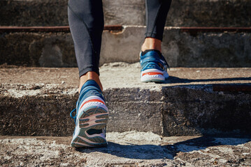 Male sprinter wearing running shoes at concrete stairs background. Sport and fitness runner athlete training at stadium