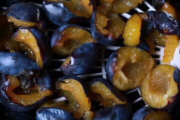 halves of plums are laid out on a tray for drying