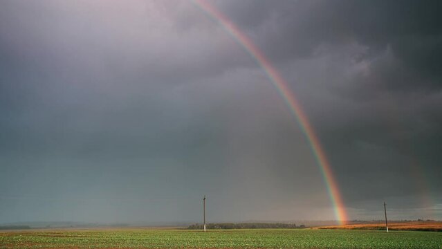 Dramatic Sky During Rain With Rainbow On Horizon Above Rural Landscape Field. Agricultural And Weather Forecast Concept. Time Lapse, Timelapse, Time-lapse. Countryside Meadow In Autumn Rainy Day.