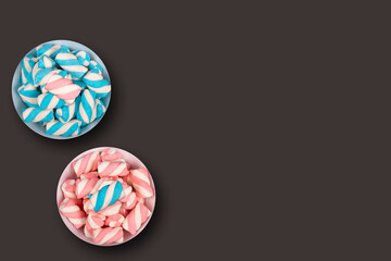 Two pots with colorful marshmallows on a dark background and copy space