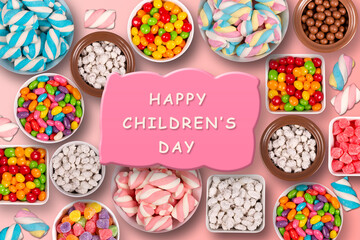 Colorful candies, marshmellows, chocolate balls in jars, lollipops and sweet peanuts written happy children's day