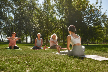 Back of woman teach mature people practicing yoga