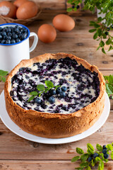 Pie with fresh and cooked blueberries on wooden table