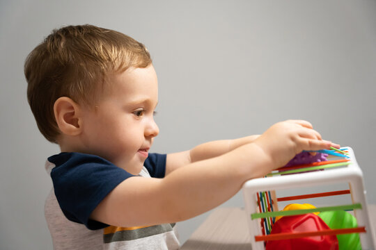 A cute toddler boy is playing a game with sensory colorful balls. Sensory and tactile activities. Games for children one and a half years old. Attentive child. Selective focus