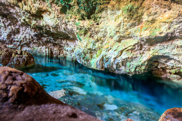 View of beautiful natural pool of crystal clear water formed in a rocky cave with stalagmites and stalagmites. Kuza cave in Zanzibar, Tanzania