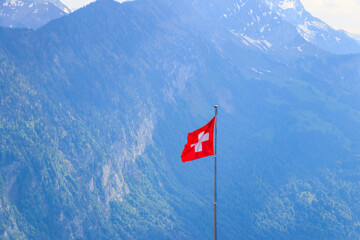 Red Swiss flag over the Swiss Alps background
