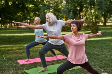Middle aged people practicing yoga in warrior pose
