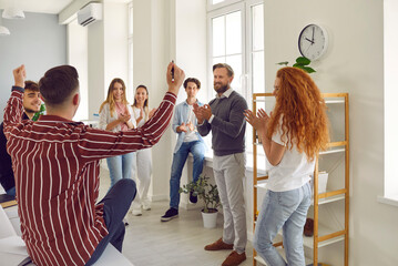 Group of happy school, college or university students together with teacher congratulating young...