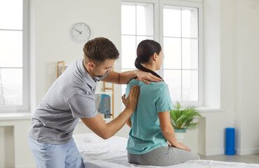Male chiropractor, physiotherapist or osteopathy specialist examining a female patient with scoliosis or back ache. Physiotherapy, modern orthopaedic therapy, scoliosis treatment concept - obrazy, fototapety, plakaty
