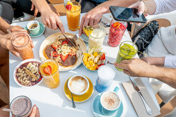 2 persons enjoying healthy brunch, delicious pancakes with sweet strawberries, banana and chocolate 