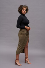 Young elegant intercultural woman in black turtleneck, long brown skirt and high heeled sandals...