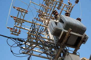 Transmission tower support high voltage power electric line compensator pylon  against blue sky.