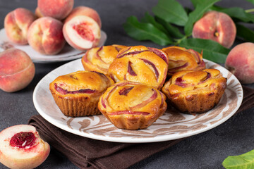 Naklejka na ściany i meble Homemade muffins with peaches on a round plate on gray background