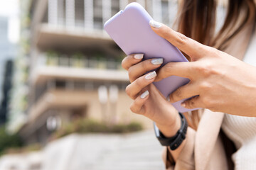 A woman is looking at the phone outside