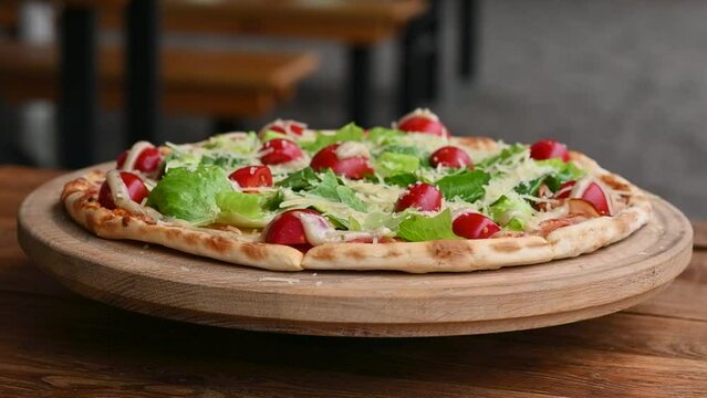 Pizza with salami and ham sausage. Italian cuisine. Side view. Free space for text. On a light wooden background. Rotates.