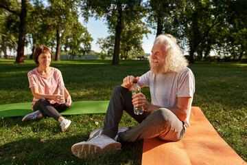 Senior woman look at grey hair man open bottle