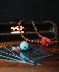Turquoise stone silver ring on top of tarot card with wood collar and wood box in the background...