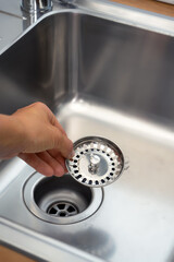 close-up of a stainless steel sink plug hole in the hands of the kitchen hostess