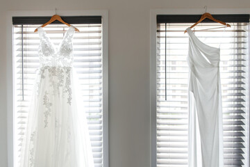 Bedroom with two women's wedding dresses for a lesbian LGBT wedding. View of beautiful white wedding dresses in the room against the background of windows for a same-sex wedding of two brides