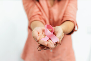 Close-up of woman's hands holding pink ribbon. Breast cancer awareness concept