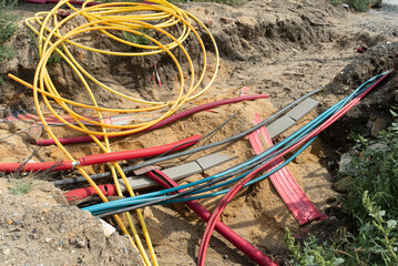 Network cables in red corrugated pipe are buried underground on the street. underground electric...