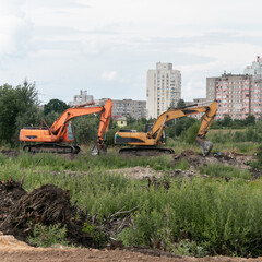 Crawler excavators dig the earth with a bucket. Drainage of swamps. Clearing the construction site. Peat mining. Road construction works.