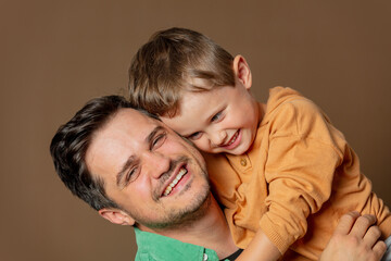 father and son cheerfully hugging on a brown background