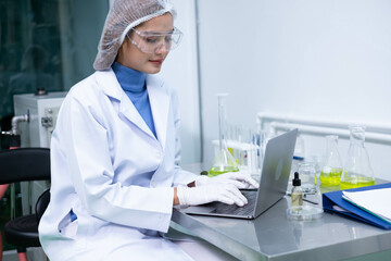 Professional Scientist holding test tube of Cannabis oil bulbs and checking vaporizer during CBD oil extraction in science lab.