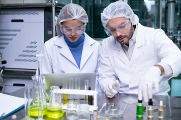 Professional Scientist holding test tube of Cannabis oil bulbs and checking vaporizer during CBD...