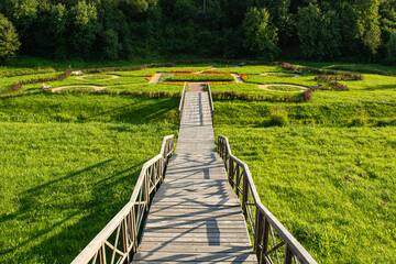 Multi-level wooden gangway in a picturesque place with a field and a forest. Summer evening before sundown. Nature landscape background