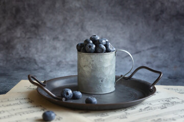 Freshly picked blueberries in a tin mug, retro style.