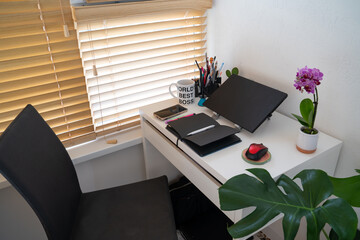 modern workplace: table desk with laptop, stationery, orchid plant, open white textbook with pen. Concept of work, work from home, study, back to school, home office