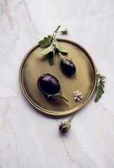 Beautiful minimalistic composition of eggplants on a round dish , marble background.