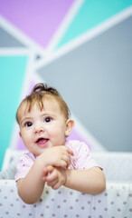 Fototapeta premium Cheerful baby standing in cradle and looking away