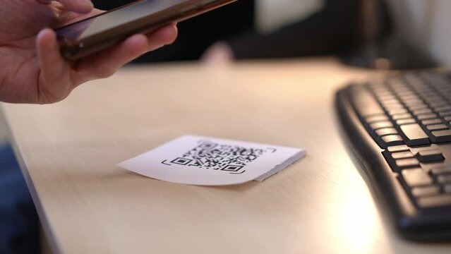 Close-up scanning QR code with smartphone app indoors. Unrecognizable Caucasian man using phone checking online web site