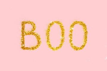 Shiny Halloween boo concept. Golden glitter on pastel light pink background. Minimalistic holiday party composition.