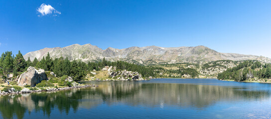 Panorama sur les rives d'un lac de montagne avec une chaine montagneuse en arrière plan