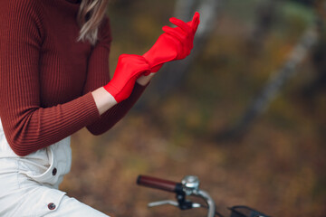 Young woman riding bicycle in red gloves and face mask at autumn park.