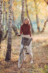 Fototapeta na wymiar Happy active young woman riding vintage bicycle in autumn park at sunset.