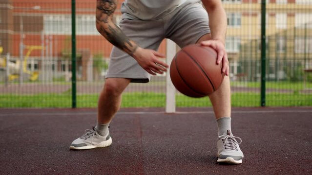 Sportsman demonstrates amazing tricks bouncing ball on basketball court