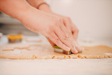 Woman hands form molds cutters ginger dough and makes delicious christmas ginger cookies. Cooking and decorating christmas dessert.