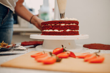 Pastry chef makes delicious red velvet cake. Cutting strawberry and decorating dessert.