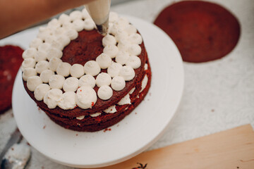 Pastry chef spreads cream and makes delicious red velvet cake. Cooking and decorating dessert.