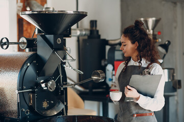 Coffee roaster machine and barista woman with tablet write pen at coffee roasting process.