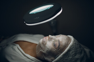 Paraffin Face Mask gauze bandage Therapy Young Woman Receiving Facial Skin Care Treatment. Beautician Pouring Wax Applying.