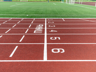 Fototapeta premium Red treadmill at the stadium with white lines